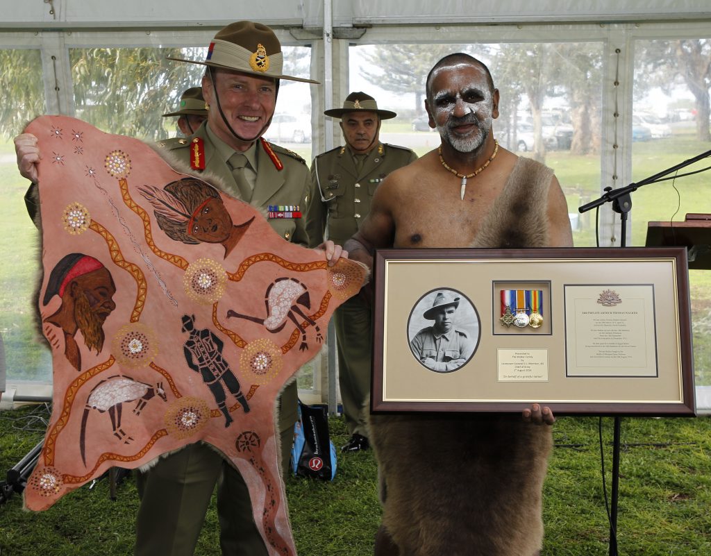 Chief of Army Lieutenant General David Morrison, AO holds up a traditional kangaroo skin warrior's cloak presented by Uncle Karno Walker, representing the Ramindjeri people of Kangaroo Island. Mr Walker displays framed memorabilia of his Great Uncle Private Arthur Thomas Walker, who was killed on the Western Front in 1916